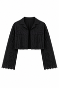 Bolero preto curto fotografado de frente em fundo claro, aberto na frente, com gola, mangas longas amplas, lese vazada com desenhos de galhos, folhas e flores em relevo, renda guipir aplicada nas mangas e dois machos frontais, um de cada lado.