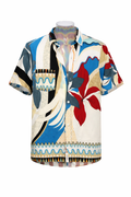 Camisa de manga curta estampada multicolorida com gola e botões frontais, com blocos em azul, bege e preto e flor vermelha em destaque.