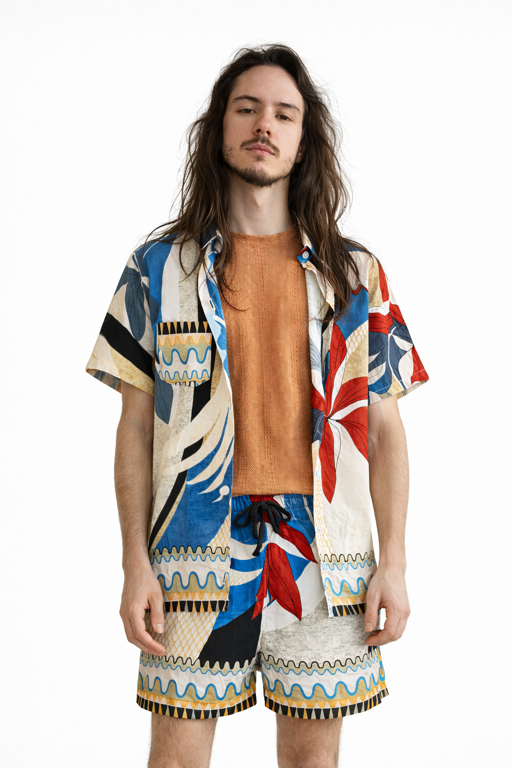 Pessoa usando camisa de manga curta estampada multicolorida aberta sobre camiseta, combinada com short coordenado do mesmo conjunto.