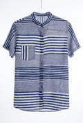 Camisa listrada azul e branca de mangas curtas, com gola, abertura frontal com botões e padronagem em blocos de listras horizontais e verticais. A peça aparece centralizada sobre fundo claro, em foto de produto para e-commerce.