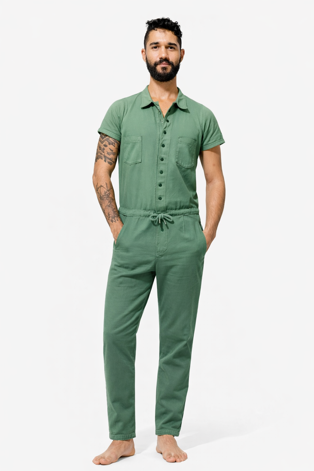 Pessoa usando macacão longo verde, com gola de camisa, fechamento por botões e ajuste por cordão na cintura.